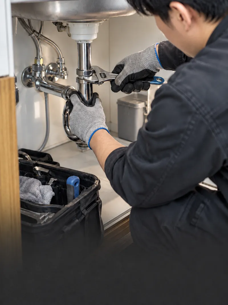 Technician repairing plumbing under a sink